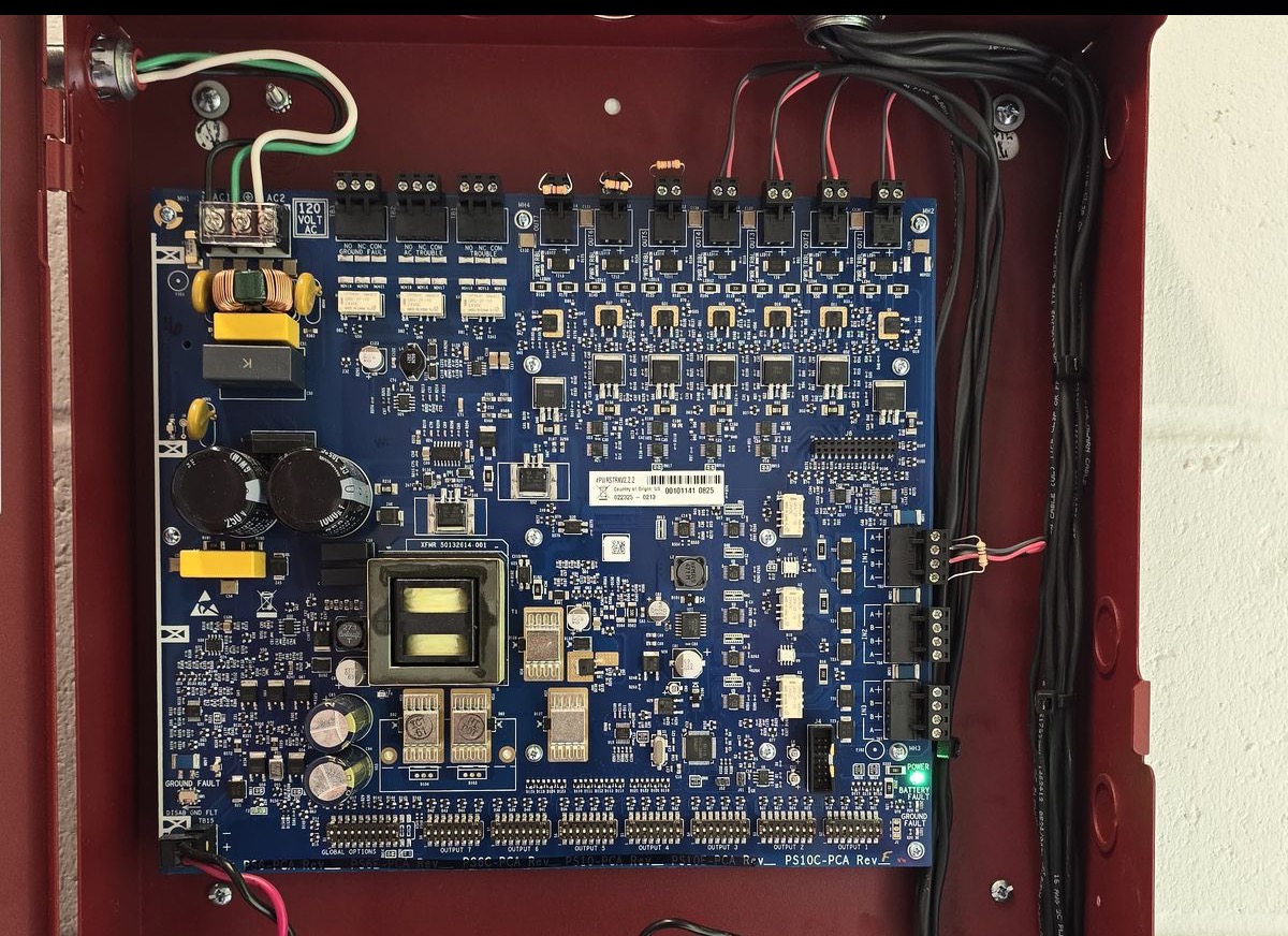 Open NAC power supply with field conductors landed on its outputs and bundled neatly down the side of the cabinet