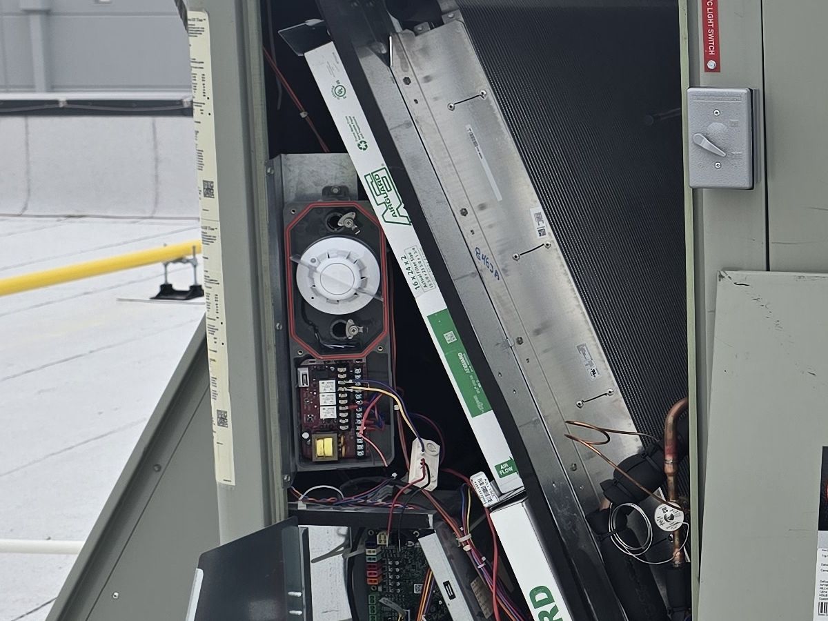 Duct smoke detector installed inside a rooftop HVAC unit with the service panel open
