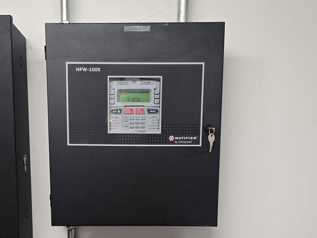 Completed wall-mounted fire alarm control panel with its display showing system normal